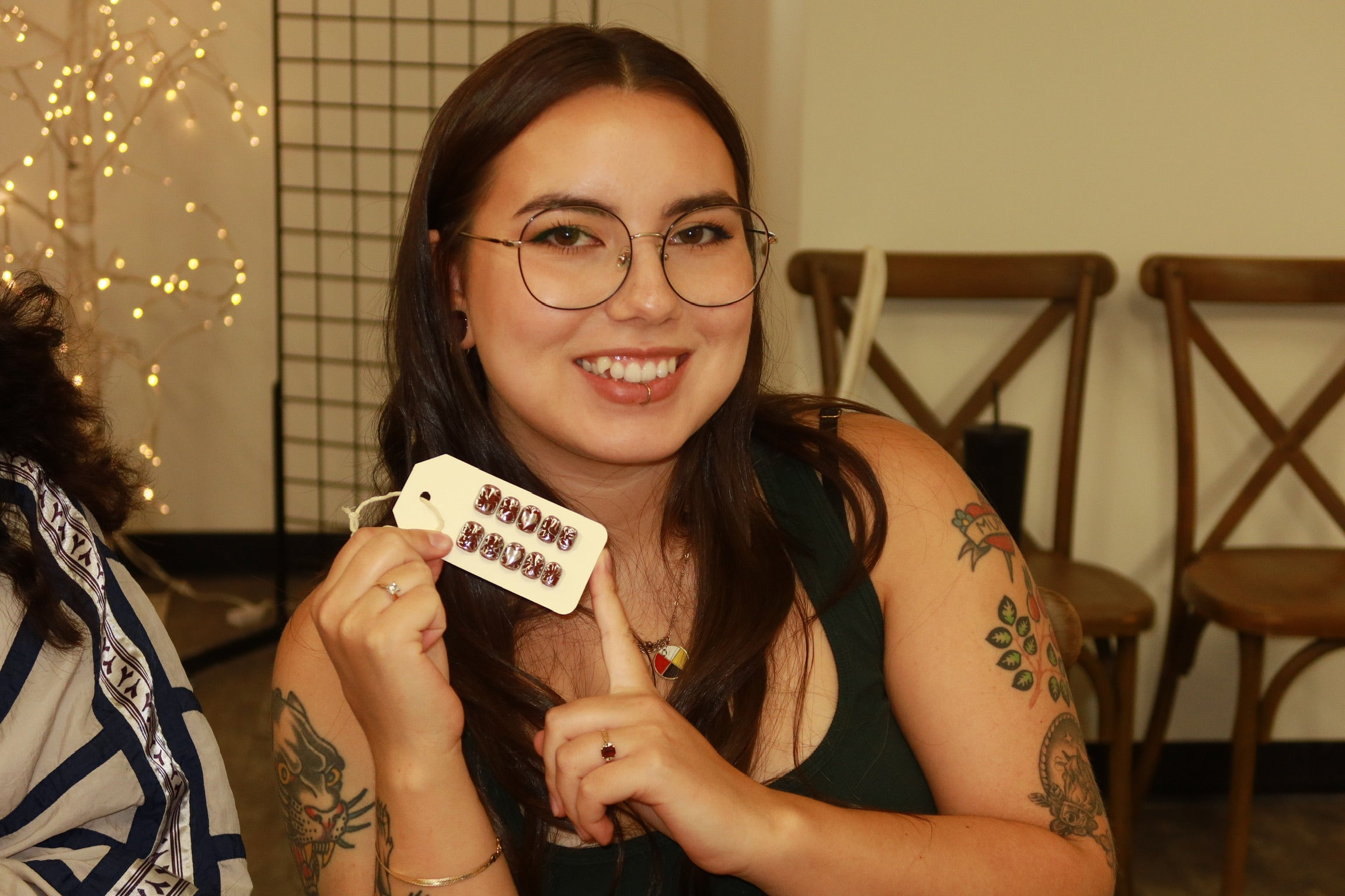 Woman holding a completed set of press-on nails, smiling.