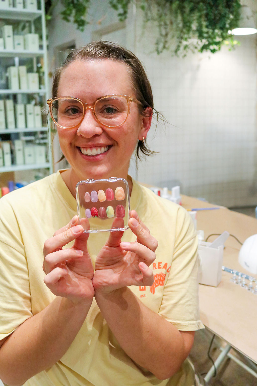 Woman holding a set of painted press-on nails, smiling.